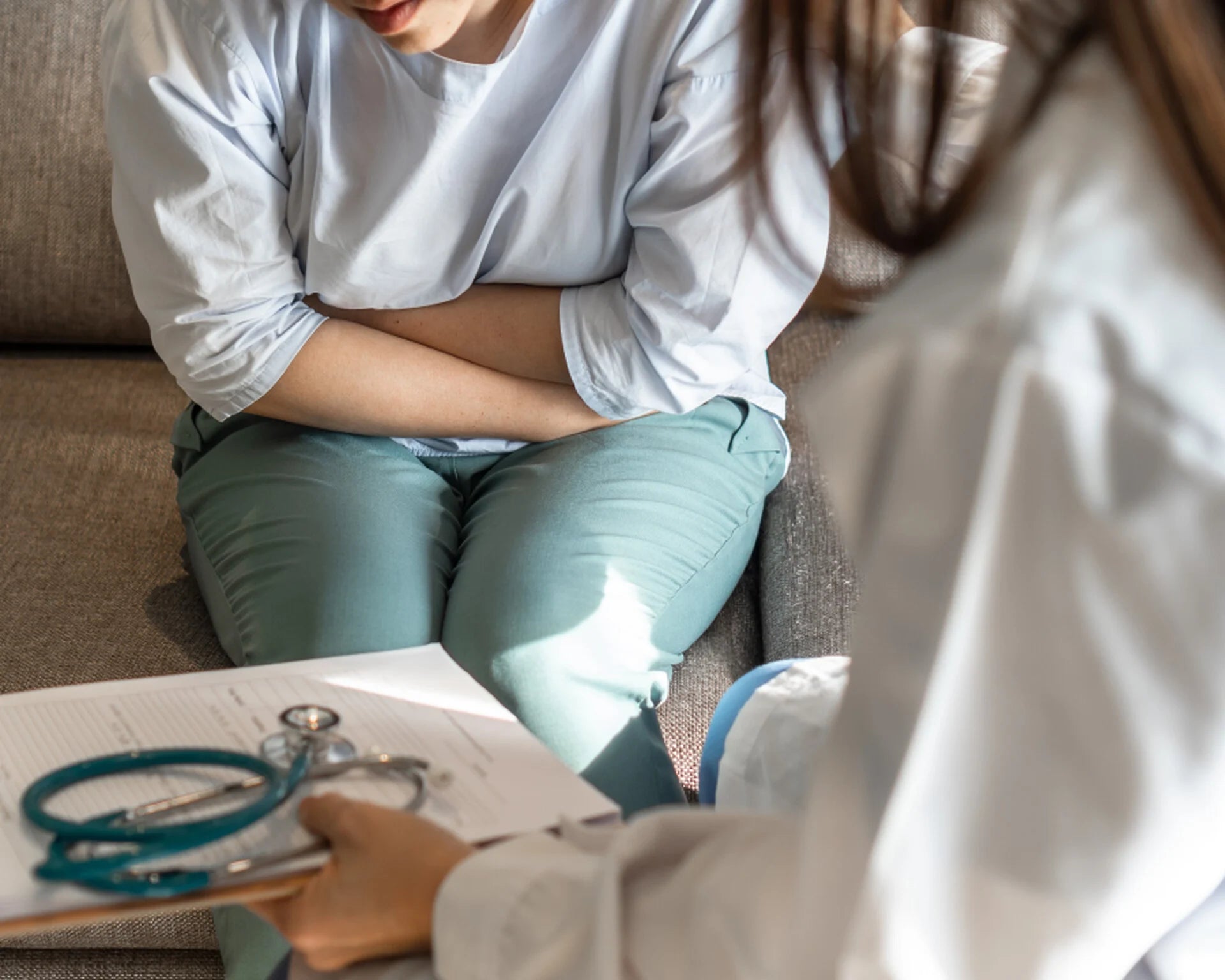 Femme en consultation médicale qui se tient le ventre, douleur