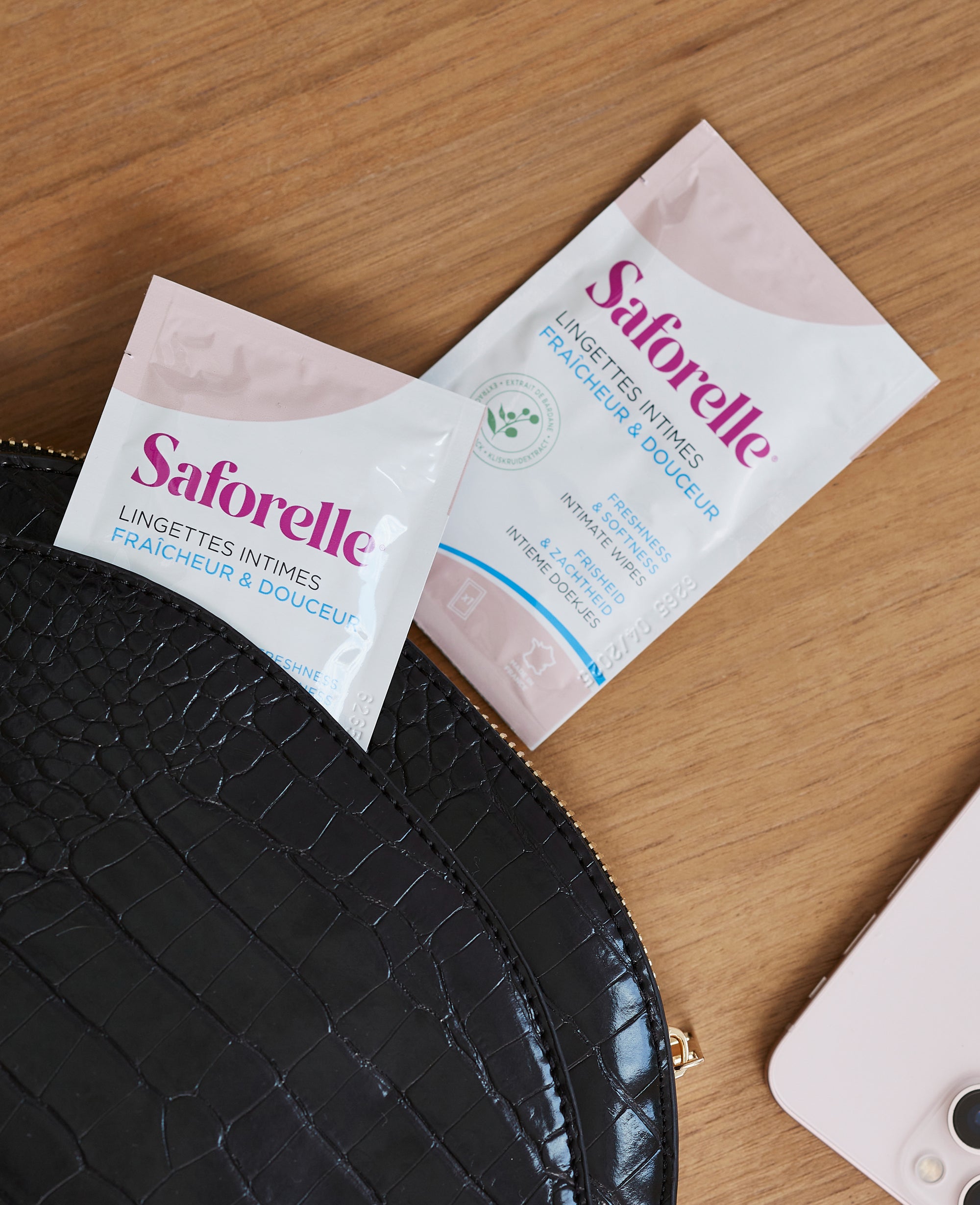 Deux sachets de lingettes intimes Saforelle posés à côté d’une trousse, hygiène intime nomade